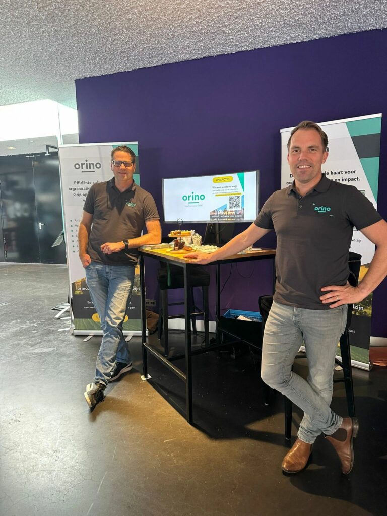 Twee mensen in een Orino-polo bij de stand van Orino op het Sociaal Werk Jaarcongres.